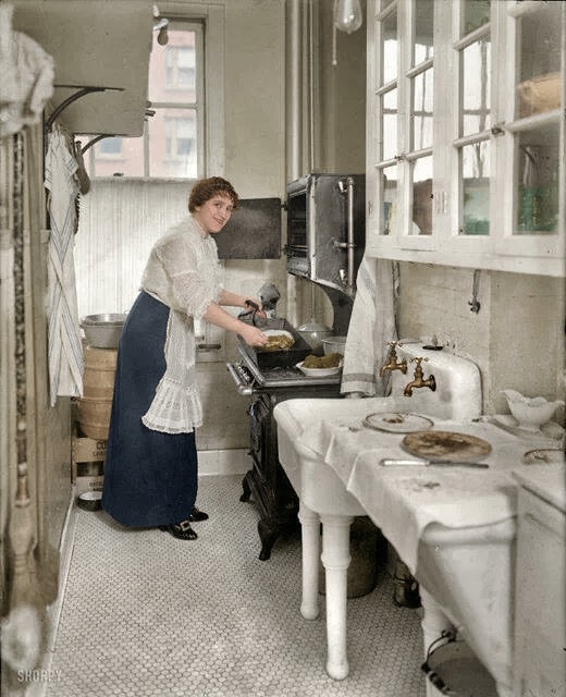 Colorized photo of a woman cooking in her kitchen in 1914