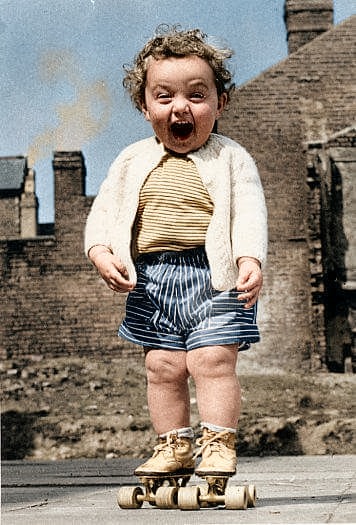 Colorized photo of a young child laughing on roller skates