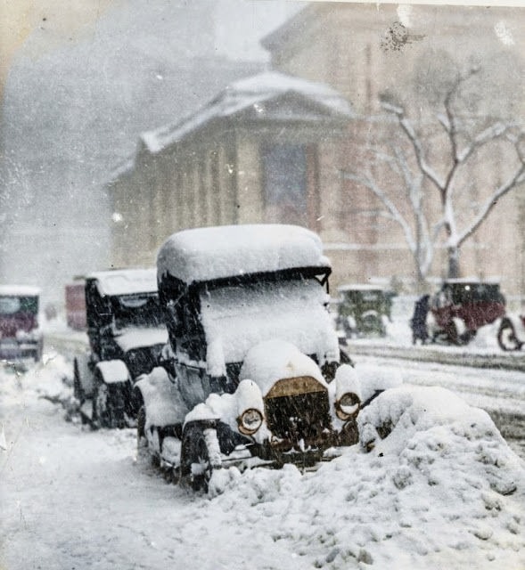 Colorized photo of cars buried in snow on a city street in the 1920s